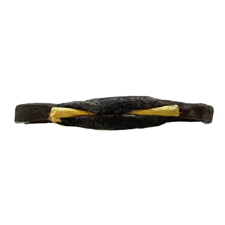 An old African wrought iron medicine bracelet gripping a rod of solid 22K gold