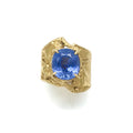 Fluid band rising up to support an oval blue sapphire