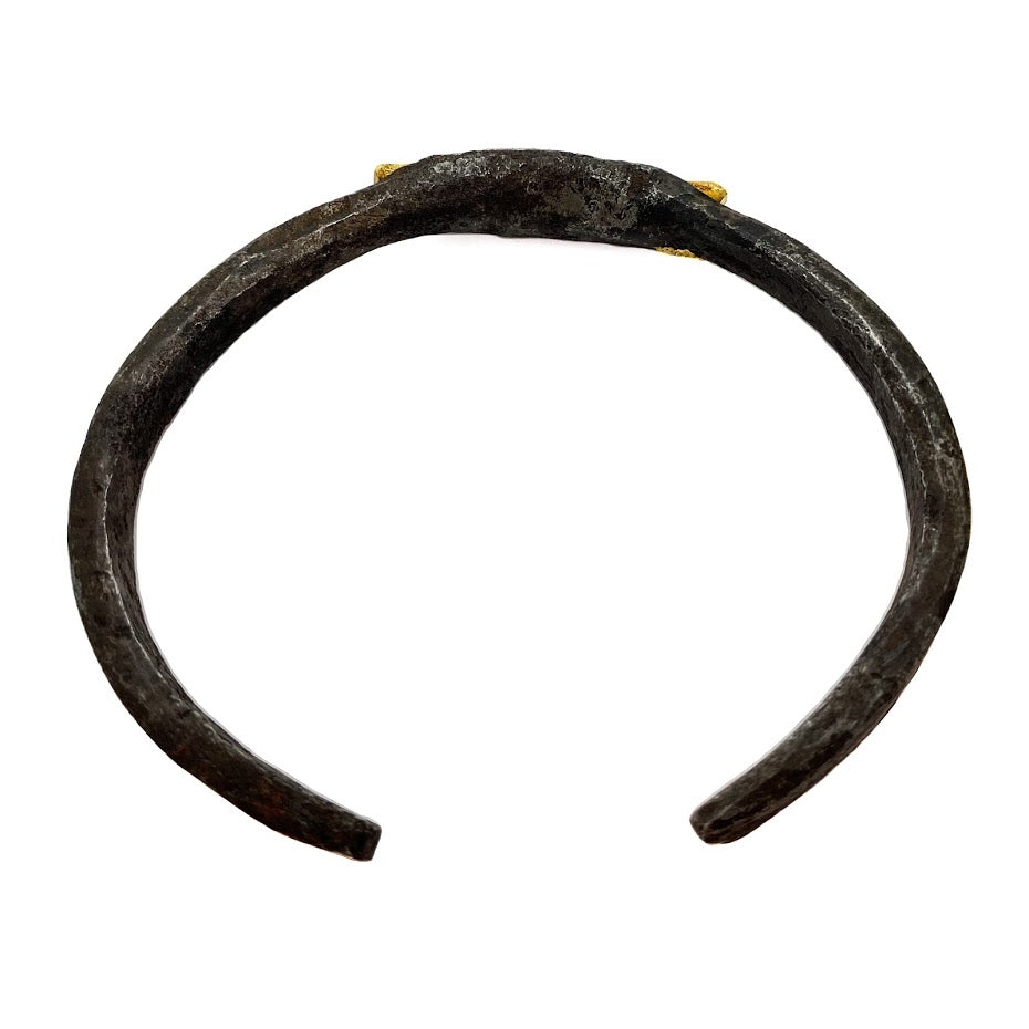 An old African wrought iron medicine bracelet gripping a rod of solid 22K gold