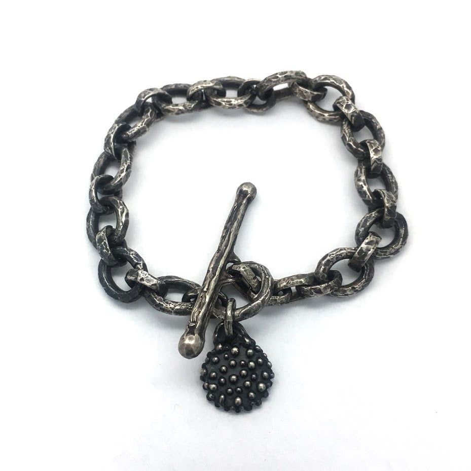 Bracelet composed of heavily textured oval links with a single dangling charm featuring a lion image from an impression of an ancient Roman stone seal